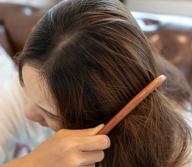 Sad young woman brushing her tangled hair.